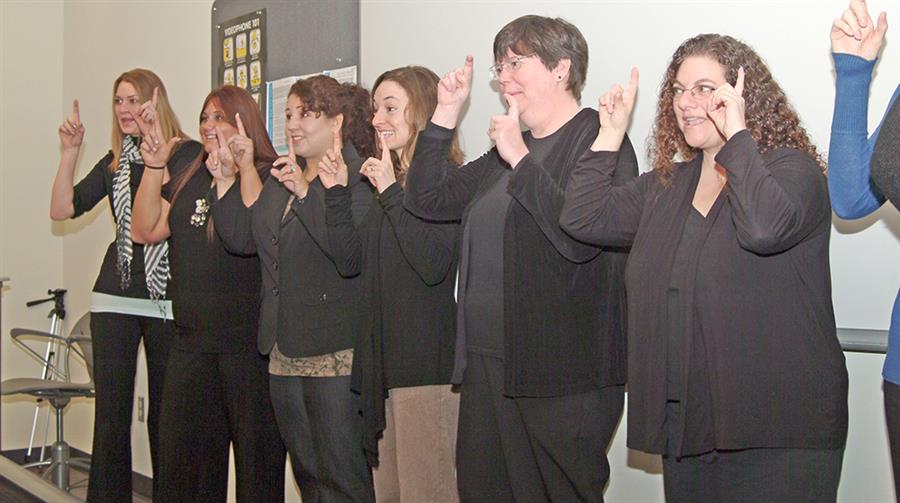 A group of women wearing black signing in front of a classroom.